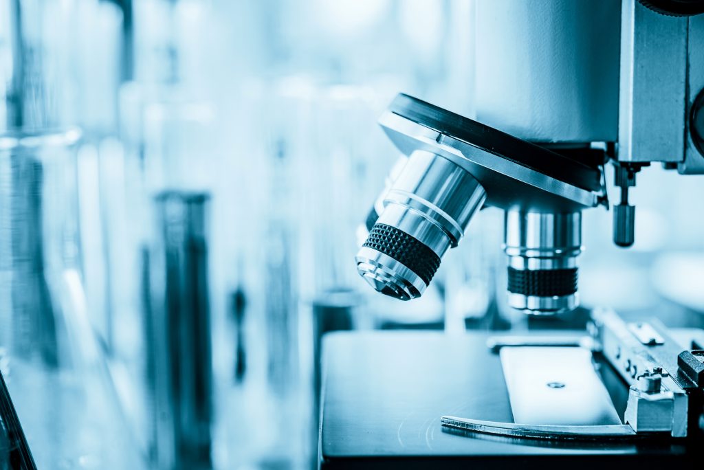 microscope in microbiology lab with laboratory glassware background for medical research or science development concept.